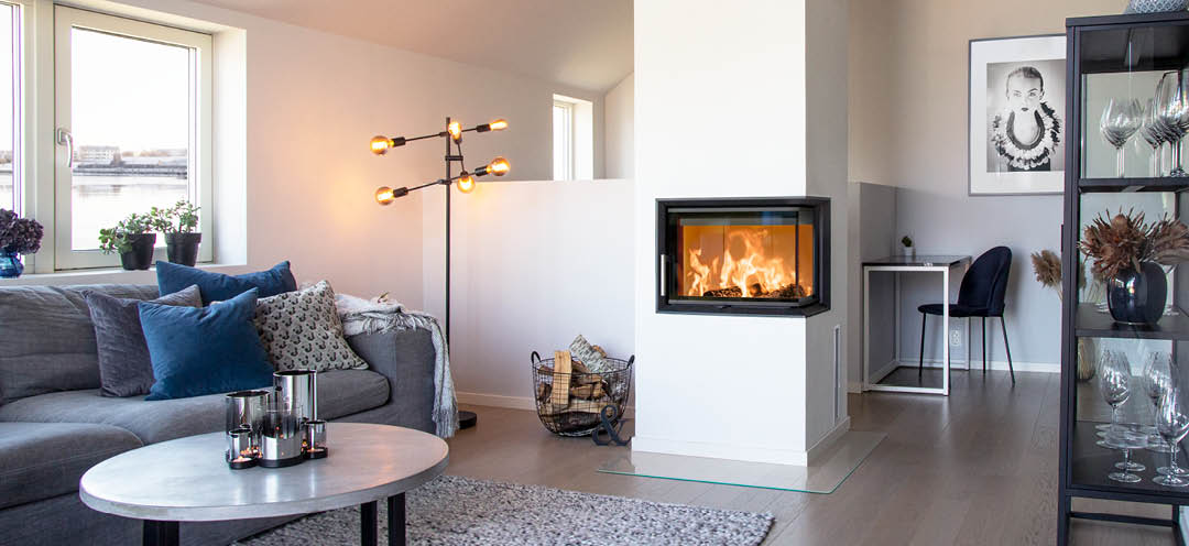 Wkład kominkowy z przeszkleniem z dwóch stron Scan 5003 w białym nowoczesnym salonie z szarą sofą i czarnymi meblami