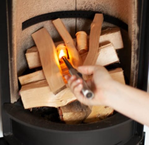 Ogień w piecu opalanym drewnem Scan 83-2 i zapalająca go kobieca dłoń