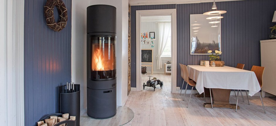 Czarny kominek umieszczony blisko niebieskiej ściany ogrzewa pomieszczenie w domu.