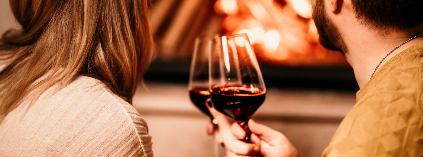 Para z winem siedząca przed kominkiem